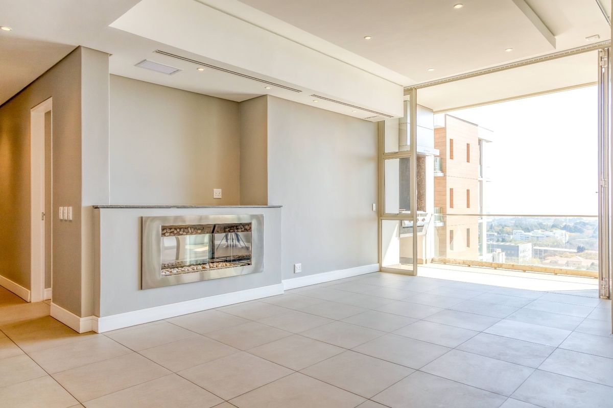 Spacious, modern living area featuring neutral tiled floors, a sleek built-in fireplace, recessed lighting, and large sliding doors opening to a balcony.