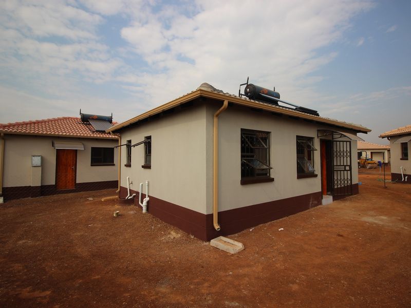 Rear view of a residential house featuring a solar water heating system, security bars on windows, and a security gate at the entrance.