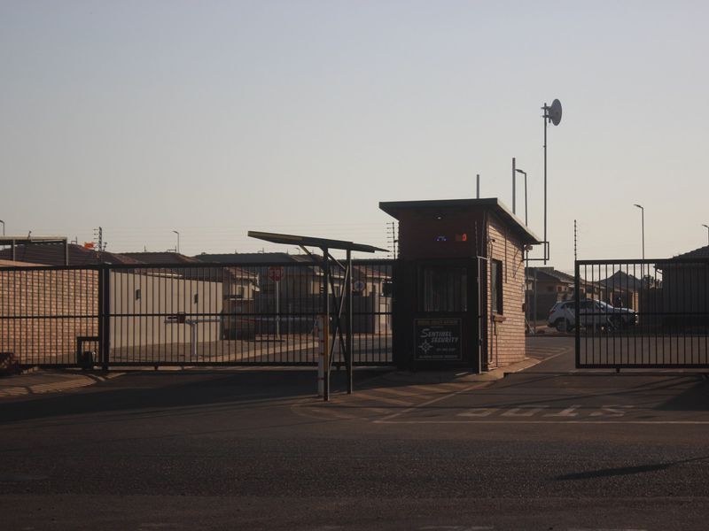 A secure gated entrance to the residential estate featuring a guard house, automated gates, and perimeter security fencing.