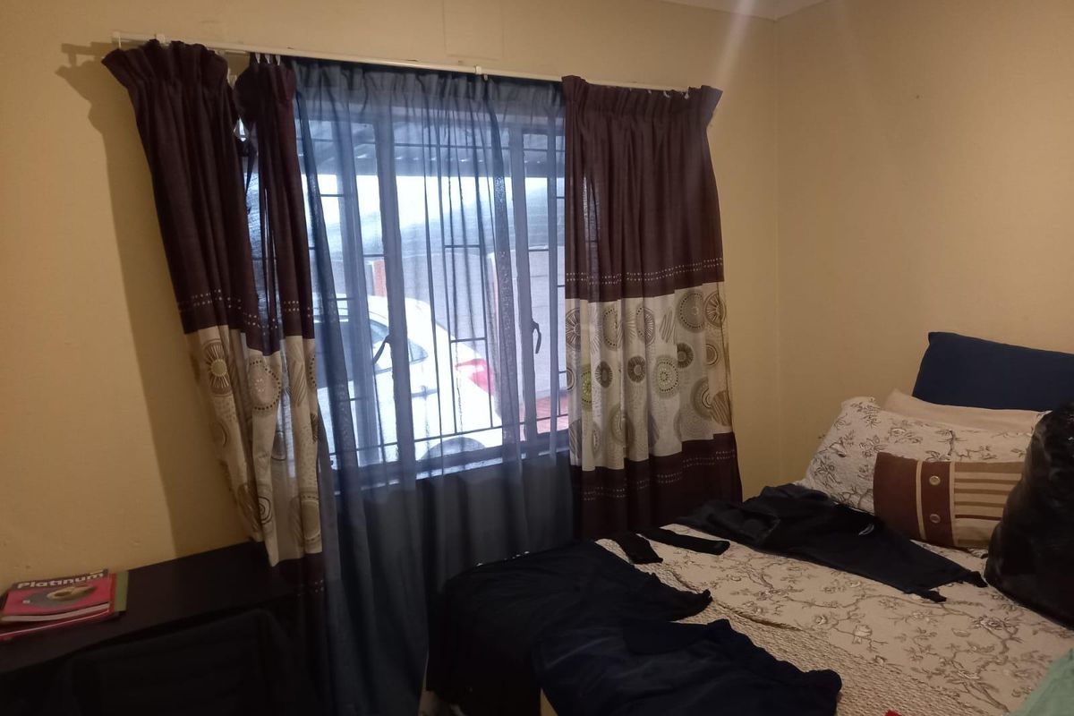 A bedroom featuring a window with installed security bars and curtain rods, providing natural light and ventilation.