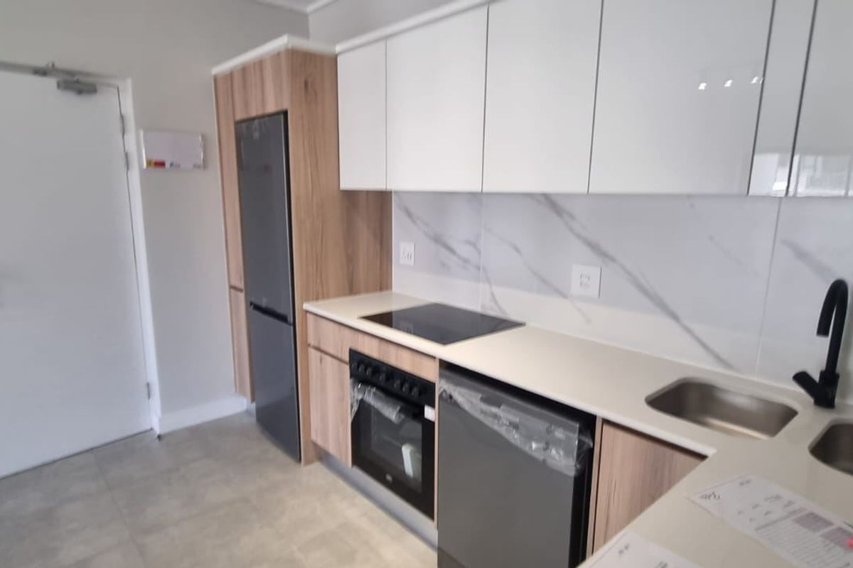 Modern kitchen featuring sleek white and wood-grain cabinetry, marble-look splashback, integrated electric hob, oven, and double sink with contemporary black fixtures.