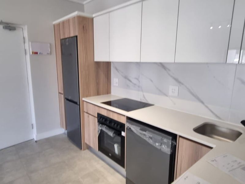 Modern kitchen featuring sleek white and wood-grain cabinetry, marble-look splashback, integrated electric hob, oven, and double sink with contemporary black fixtures.