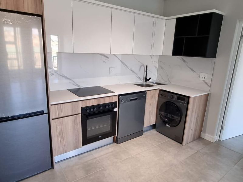 Modern kitchen featuring sleek white and wood-grain cabinetry, stone countertops, marble-look splashback, and integrated appliances including an oven and hob.