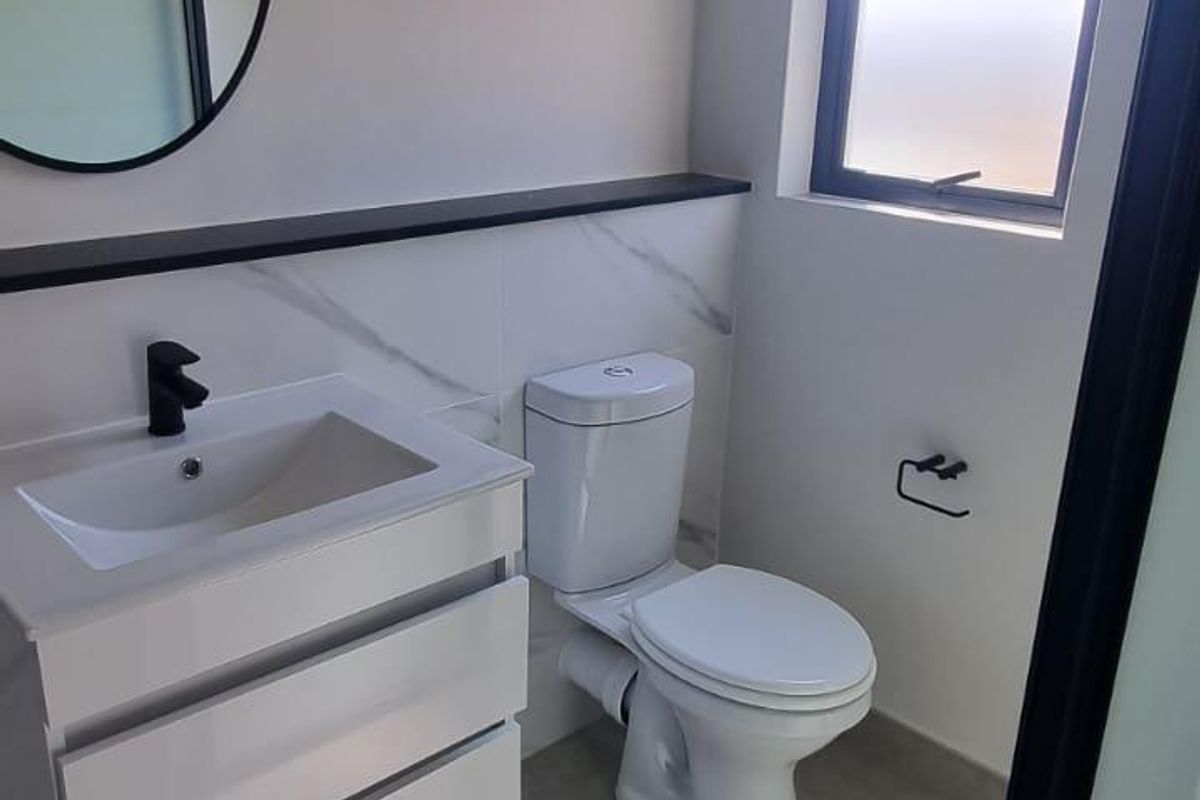 Modern bathroom featuring a wall-mounted vanity with a black mixer tap, marble-look splashback, and neutral floor tiles.