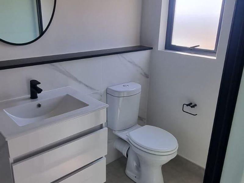Modern bathroom featuring a wall-mounted vanity with a black mixer tap, marble-look splashback, and neutral floor tiles.