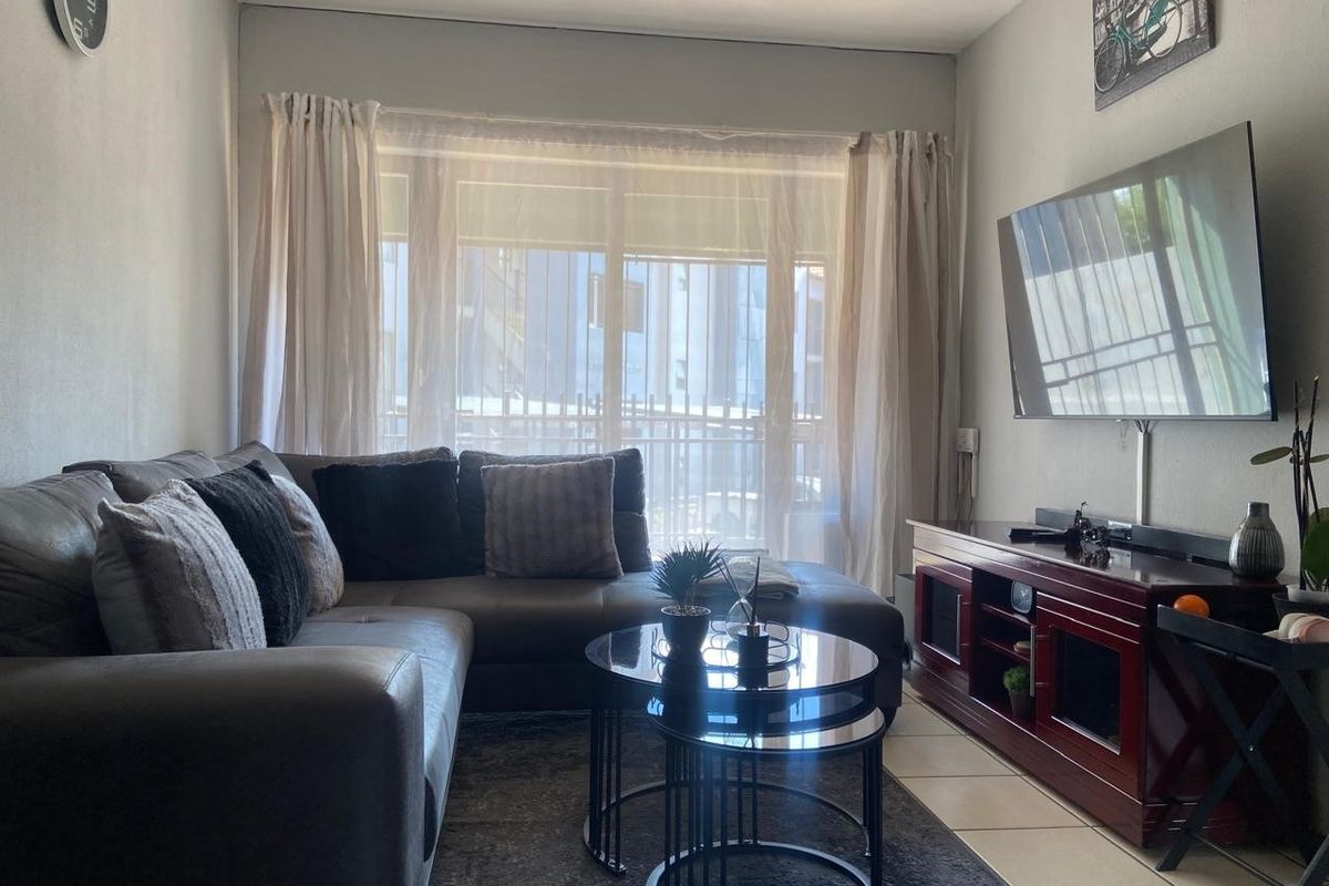 A comfortable living room featuring tiled flooring and a large sliding glass door that provides natural light.