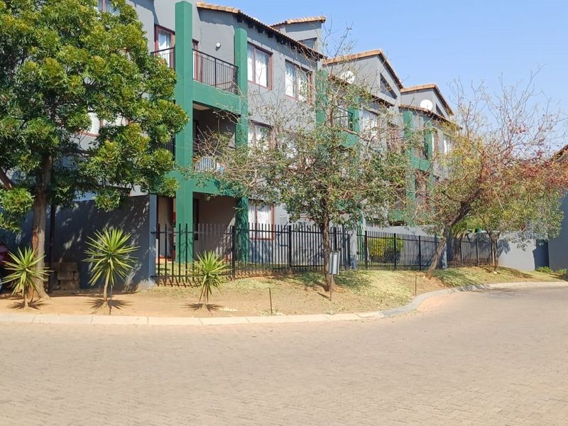 Exterior view of a multi-story apartment complex featuring paved driveway access, covered parking, and balcony access for residents.