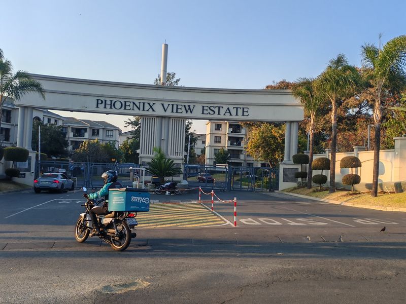The main entrance gate and security access point for Phoenix View Estate, featuring structured signage and perimeter fencing.