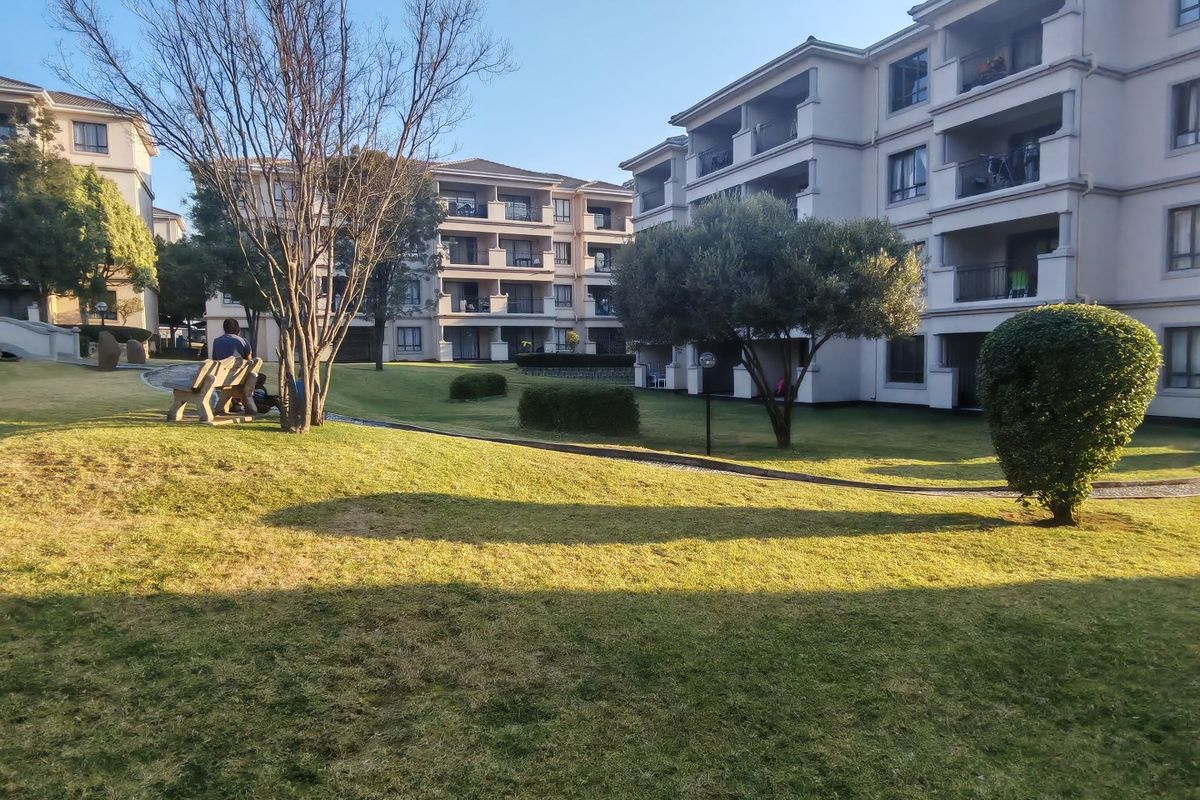 A view of the well-maintained communal garden area and landscaped lawns situated between multi-story apartment blocks.
