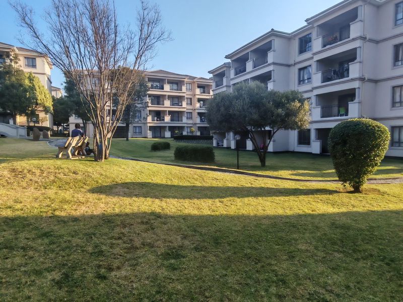 A view of the well-maintained communal garden area and landscaped lawns situated between multi-story apartment blocks.