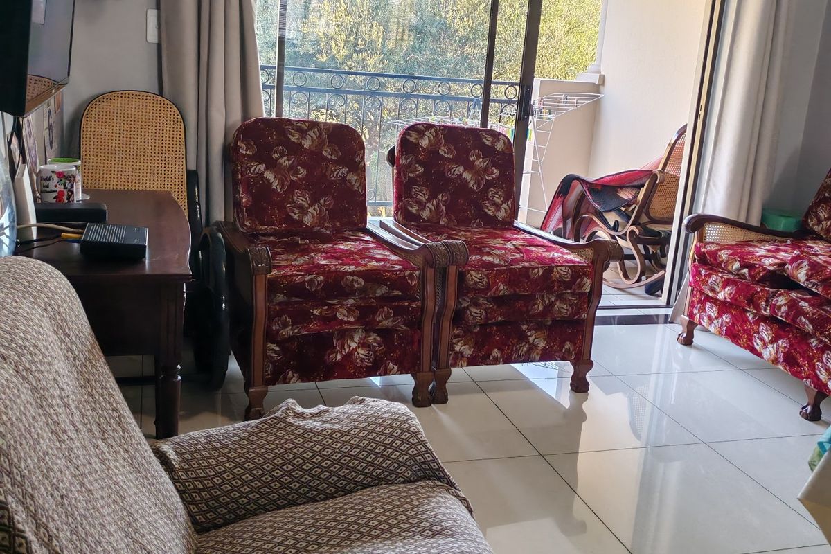 A living room featuring large format floor tiles and a sliding glass door providing direct access to an outdoor balcony area.