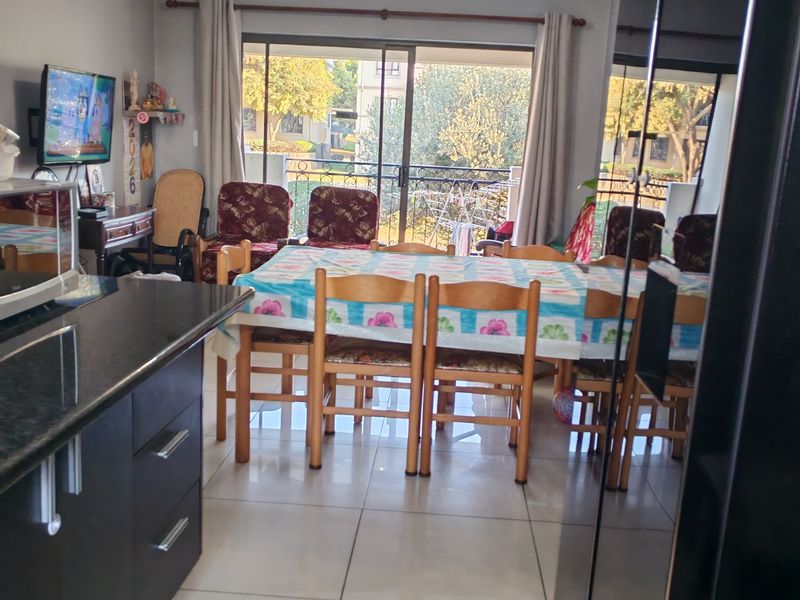 Open-plan living and dining area featuring tiled flooring, granite kitchen countertops, and direct access to a balcony through sliding glass doors.