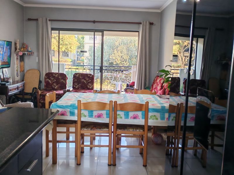 Open plan living and dining area featuring tiled flooring, modern kitchen cabinetry with granite countertops, and a sliding glass door leading to a balcony.