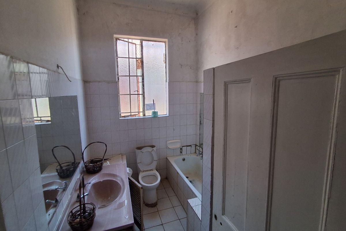 A dated bathroom featuring a built-in vanity, bathtub, and toilet, requiring significant renovation and cosmetic updates to restore its functionality and appeal.