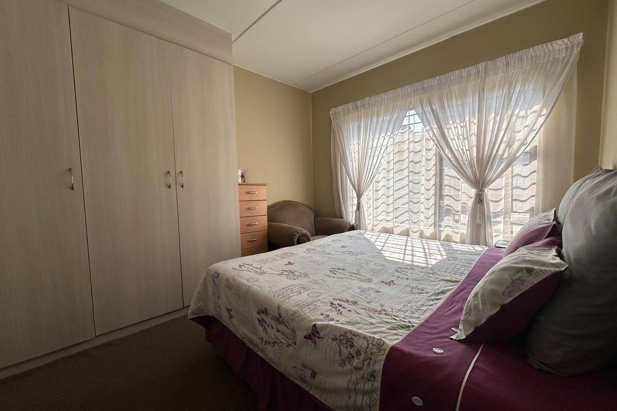 A bedroom featuring built-in wardrobes and natural light through a window with curtain rails.