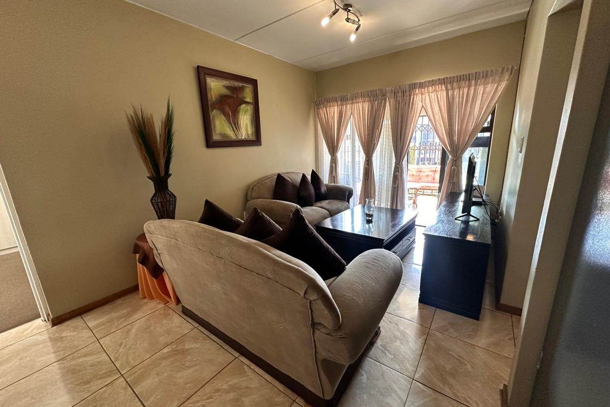 A comfortable living room featuring tiled flooring and a sliding glass door that provides access to an outdoor area.