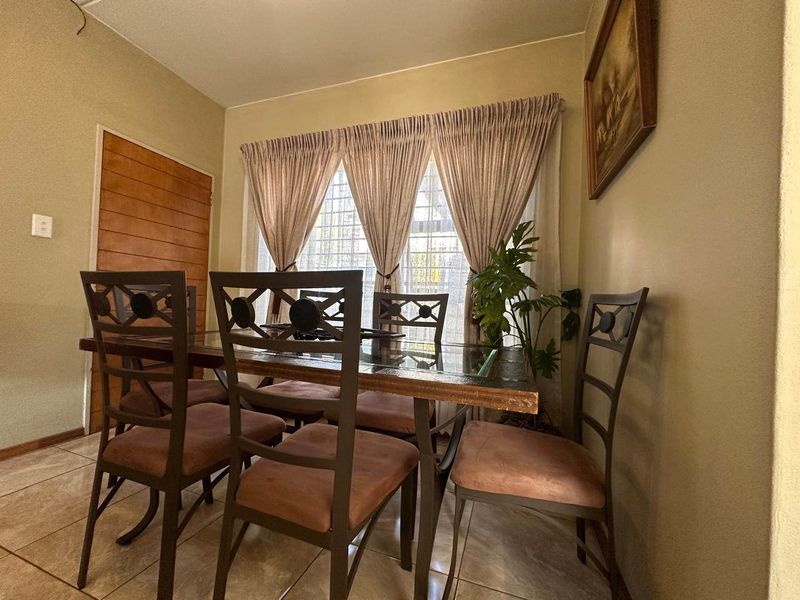 A dining room featuring tiled flooring and a wooden door, providing a functional space for meals.