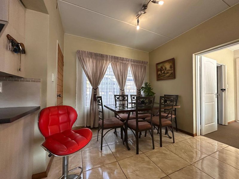 A functional dining area featuring tiled flooring and direct access to adjacent rooms, providing a practical space for meals.