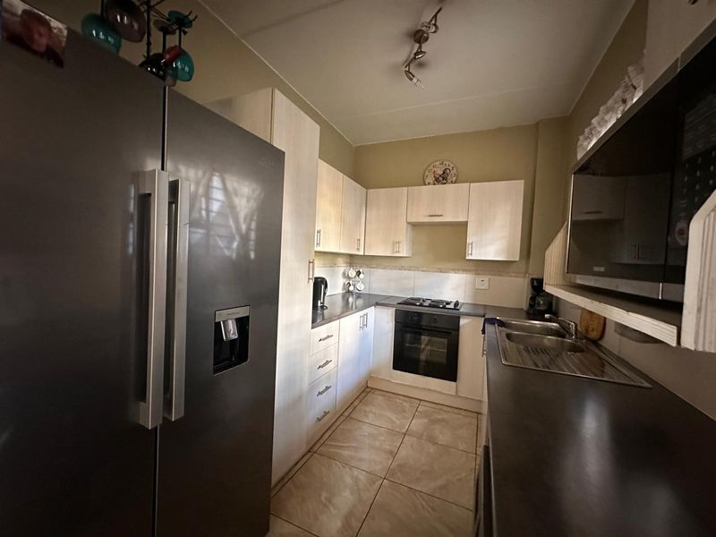 A functional kitchen featuring light-toned cabinetry, dark countertops, built-in oven with gas hob, and tiled flooring.