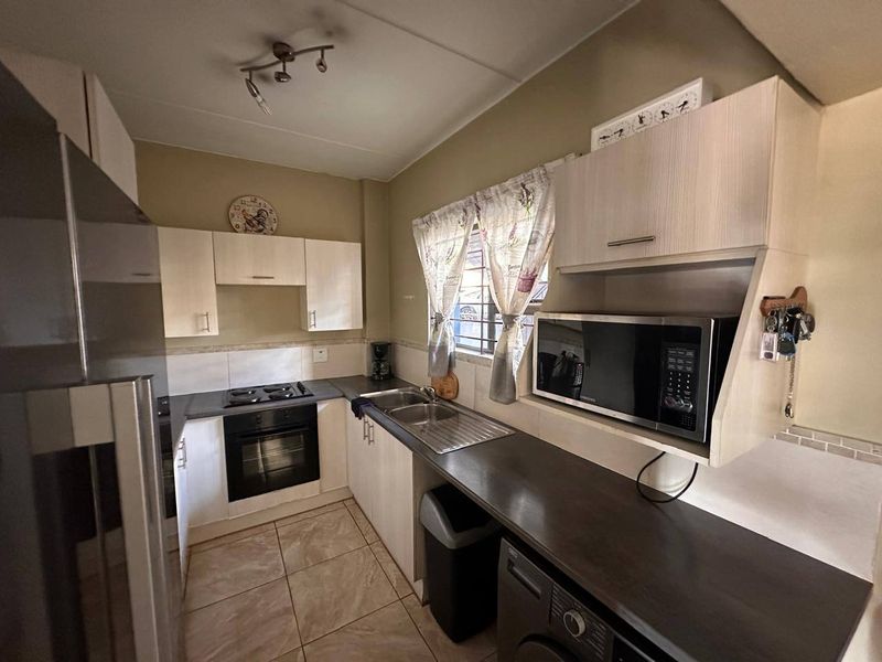 Functional kitchen featuring built-in cabinetry, laminate countertops, a stainless steel sink, built-in oven, and gas hob with tiled flooring and backsplash.