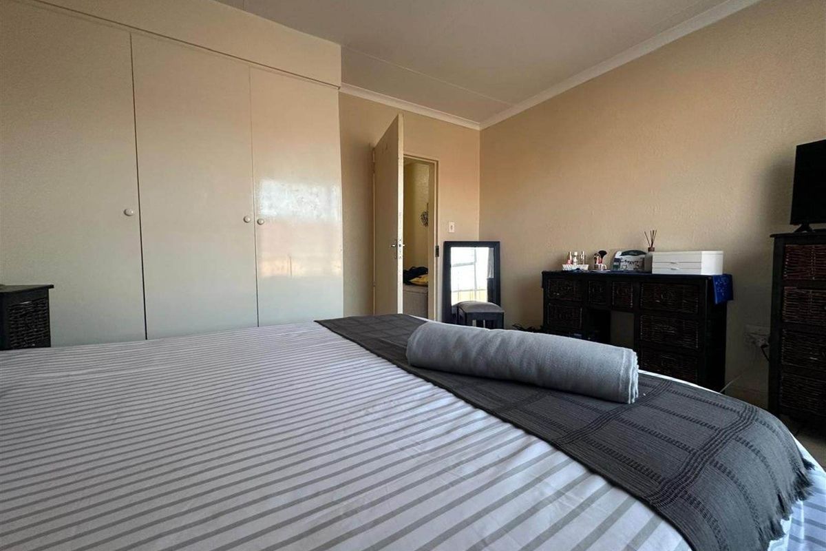 A functional bedroom featuring built-in cupboards and coved ceiling detailing, providing ample storage space.