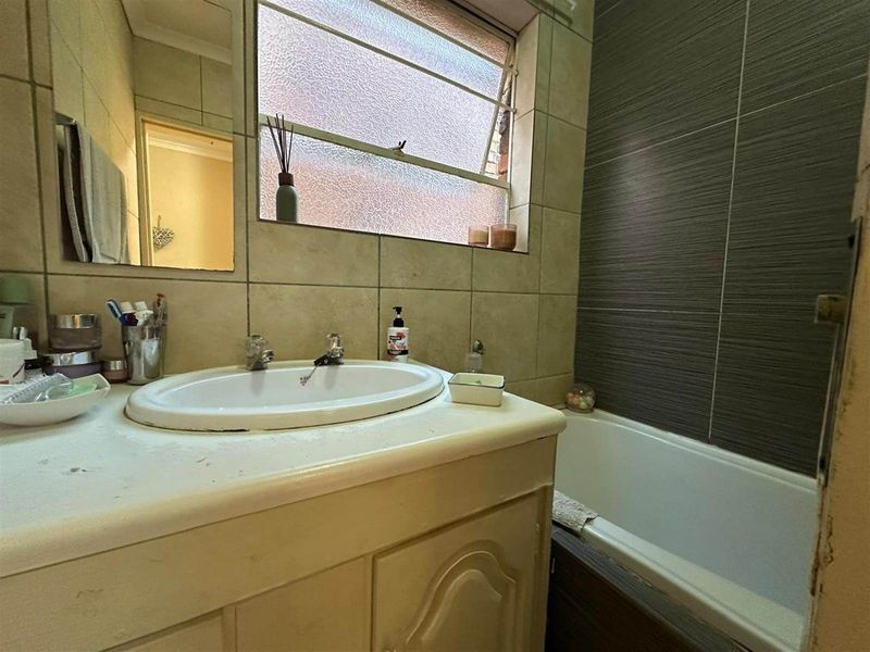 A functional bathroom featuring a vanity with a drop-in basin, a bathtub, and tiled wall finishes.