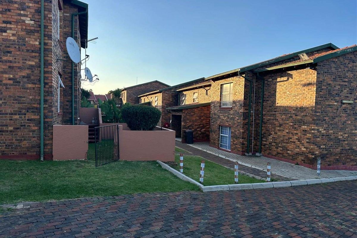 Exterior view of the apartment complex featuring face brick construction, paved pathways, and private courtyard access.
