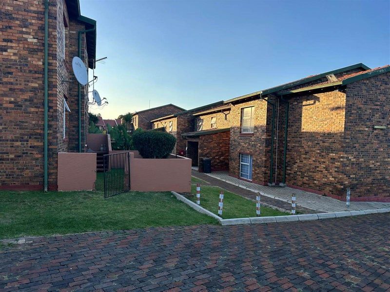 Exterior view of the apartment complex featuring face brick construction, paved pathways, and private courtyard access.