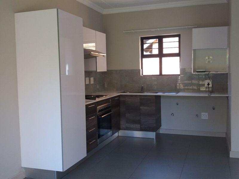 Modern kitchen featuring sleek two-tone cabinetry, built-in oven and hob, tiled splashback, and neutral floor tiles in an open-plan layout.