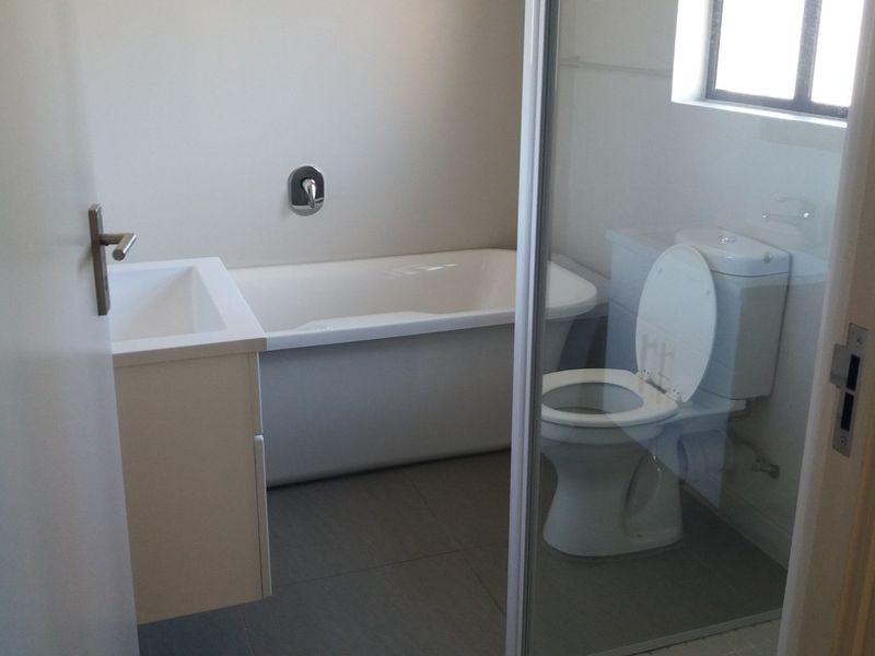 A clean, functional bathroom featuring a bathtub, vanity, toilet, and a separate shower enclosure with tiled flooring.