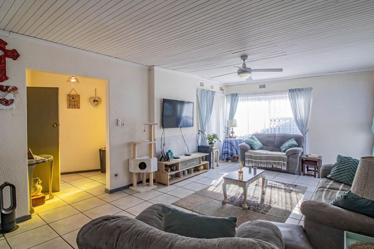 A spacious living room featuring tiled flooring, a tongue and groove ceiling, and a ceiling fan, offering a comfortable and functional layout.
