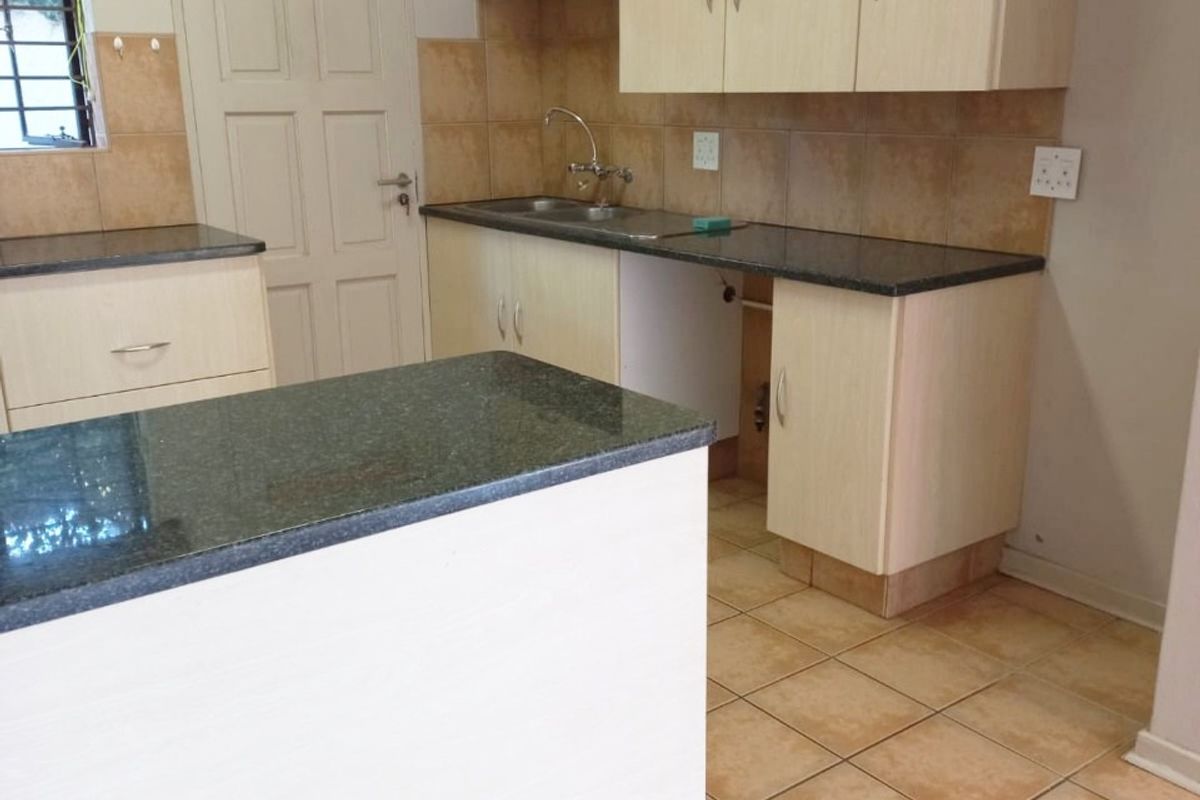 A functional kitchen featuring granite countertops, light-toned cabinetry, tiled backsplash, and ceramic flooring, offering a clean and practical layout for culinary activities.