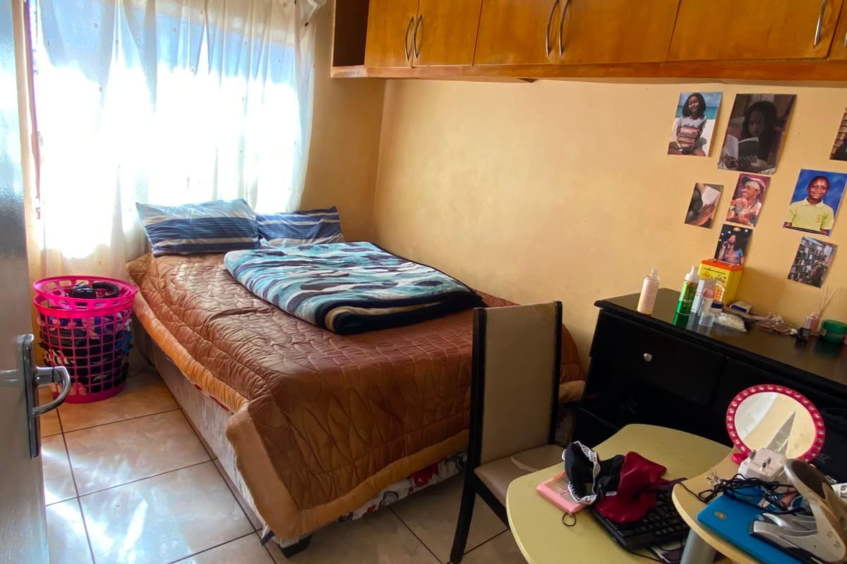 A compact bedroom featuring tiled flooring and built-in overhead storage cabinetry.