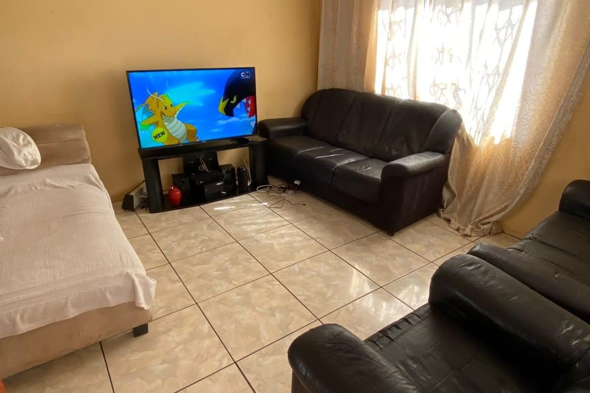 A living room featuring ceramic floor tiles and coved ceiling cornices, requiring cosmetic updates to the wall finishes.