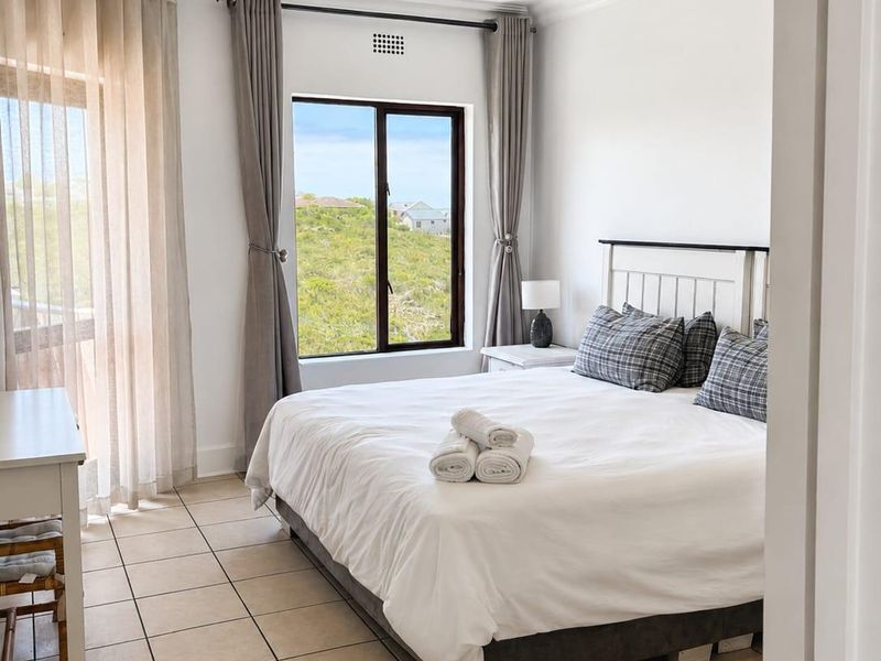 A bright and well-maintained bedroom featuring tiled flooring, a ceiling fan, recessed lighting, and direct access to an outdoor area through a sliding glass door.