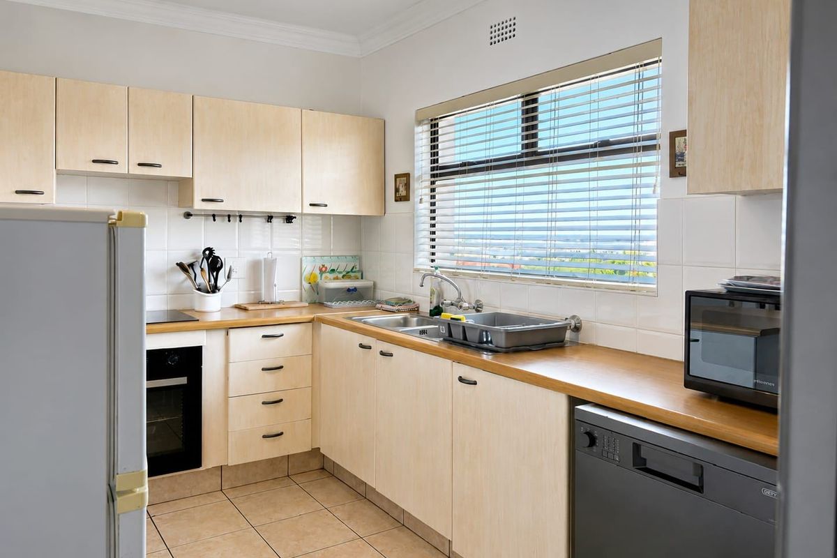 A functional kitchen featuring light wood cabinetry, wooden countertops, tiled backsplash, and integrated appliances, offering a clean and practical workspace.