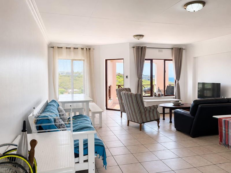 Spacious open-plan living area featuring tiled flooring, neutral walls, and direct access to a balcony with scenic views.