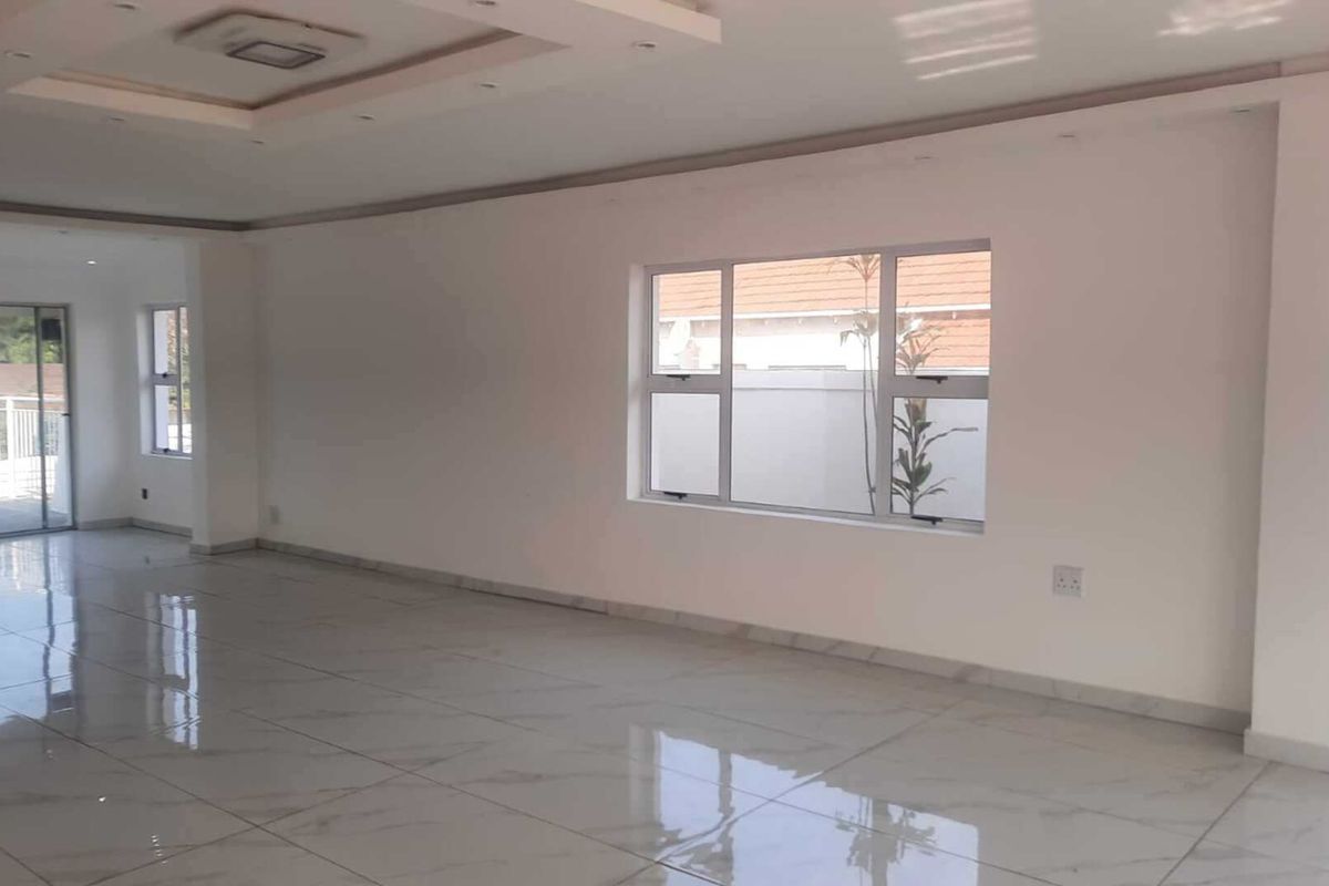 Spacious, open-plan living area featuring modern tiled flooring, recessed ceiling details, and large windows providing ample natural light.