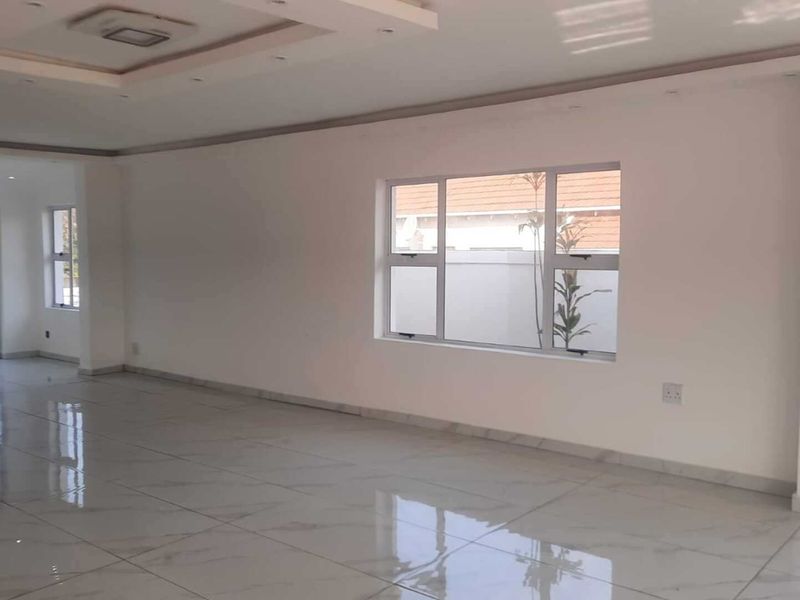 Spacious, open-plan living area featuring modern tiled flooring, recessed ceiling details, and large windows providing ample natural light.