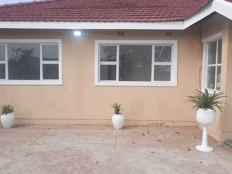 Rear exterior view of the house featuring a concrete patio area, white aluminium window frames, and a tiled roof.