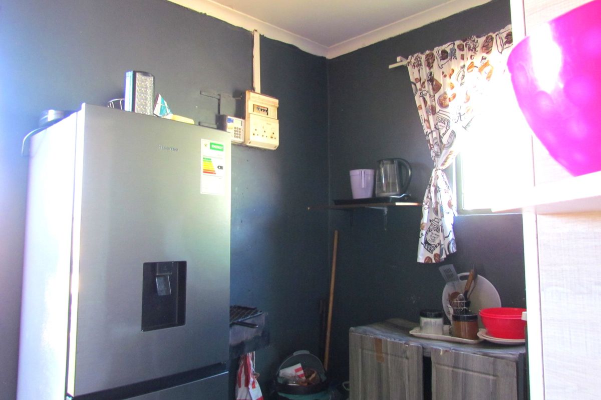A small kitchen area featuring dark painted walls, built-in cabinetry, and an exposed electrical distribution board.