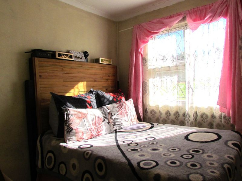 A bedroom featuring a window with security bars, requiring cosmetic updates to the wall finishes and ceiling cornices.