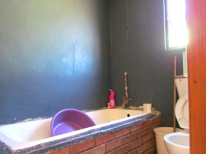 A dated bathroom featuring a built-in brick-encased bathtub and toilet, requiring significant renovation and finish improvements to modernize the space.