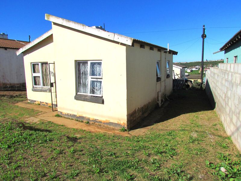 Front exterior view of a detached house featuring a corrugated metal roof, security bars on windows, and a concrete perimeter wall.