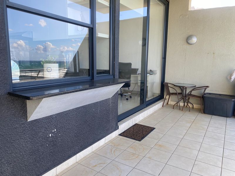 A covered balcony featuring tiled flooring, a granite breakfast bar, and sliding glass doors providing access to the interior living space.