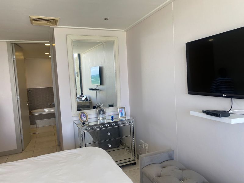 A well-maintained bedroom featuring tiled flooring, recessed lighting, ducted air conditioning, and direct access to an en-suite bathroom.