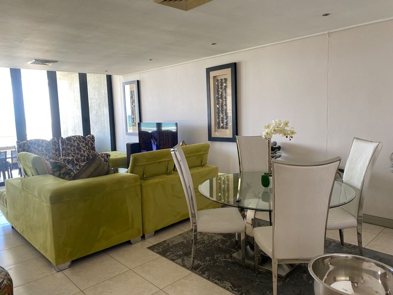 Open-plan living and dining area featuring tiled flooring, recessed lighting, and large sliding glass doors leading to an outdoor space.