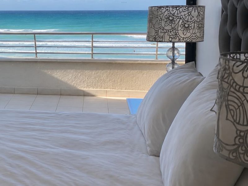 A bedroom featuring direct access to a balcony with a metal balustrade and expansive ocean views.