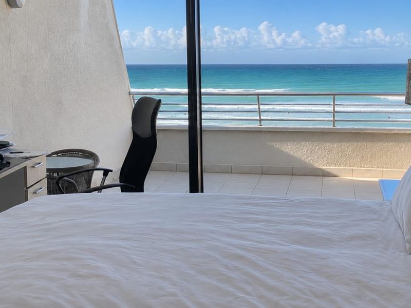 A bedroom featuring a large sliding glass door that opens onto a balcony with direct ocean views.