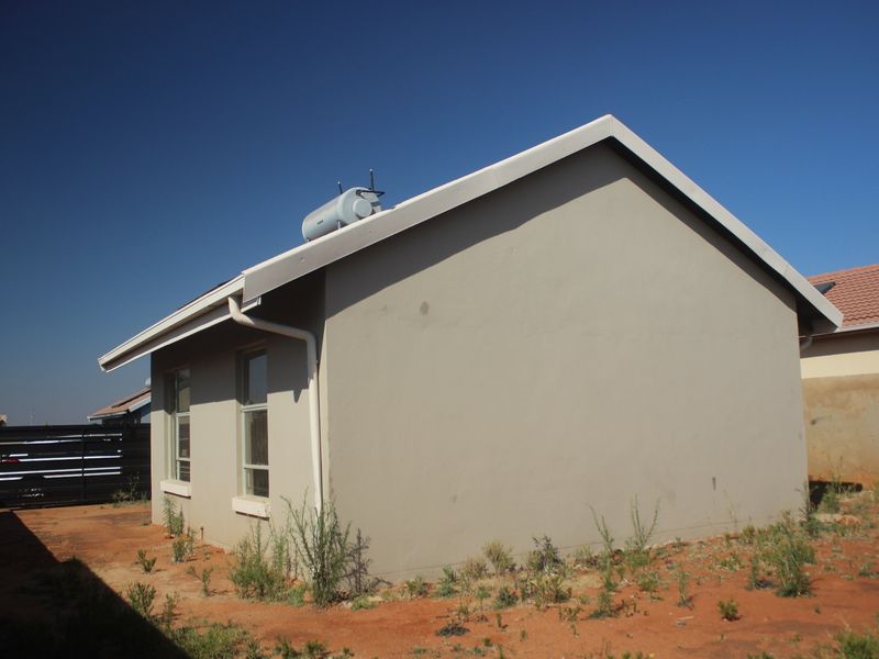 Side and rear view of the house featuring a solar water heater on the roof and basic exterior finishes.